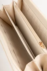 Billetera color beige con cierre de cremallera y apliques de tachas doradas en forma de corazón.