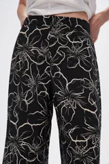 Pantalón capri negro con estampado floral en color crema, de corte ancho y tiro alto.