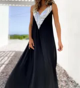 Vestido largo negro con escote en V y breteles finos. Presenta un aplique triangular de lentejuelas plateadas en la parte superior.