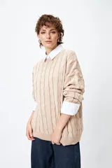 Sweater color beige con diseño de ochos en relieve, cuello redondo y corte oversize.