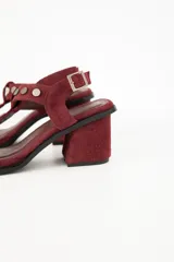 Sandalias de cuero color bordó, con taco cuadrado y tiras con apliques metálicos dorados.