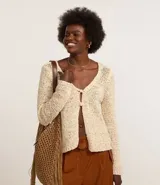 Cardigan color crema confeccionado en tejido de punto con algodón BCI más sostenible. Tiene cuello en V, manga larga y cierre frontal con dos botones.