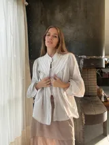 Camisa blanca de algodón con cuello mao, mangas largas abullonadas y cierre frontal con botones.