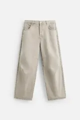 Pantalón de jean color beige, de corte amplio y tiro alto. Tiene cinco bolsillos, cierre frontal con botones y detalle de costuras laterales dobles.