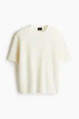 Remera color crema de punto texturizado, con cuello redondo y mangas cortas.