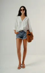 Blusa blanca de manga tres cuartos con cuello en V y textura sutil, corte holgado.