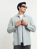 Sobrecamisa verde de manga larga con cuello camisero, cierre frontal con botones y bolsillo de parche en el pecho.