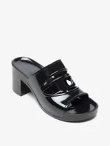 Sandalia tipo mule negra de charol, con plataforma y taco ancho. Presenta un diseño calado en la parte superior con un corte que simula un logo o forma geométrica.