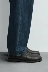 Zapato de vestir de cuero negro, tipo derby con cordones, de horma redonda y suela con ligero tacón.