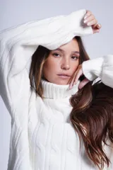 Sweater rojo de punto trenzado con cuello alto.