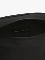 Riñonera negra Tommy Hilfiger con logo metálico en el frente, correa ajustable con cierre de apertura fácil, panel de malla acolchado en la parte trasera y bolsillo interior con cremallera. Confeccionada en poliéster.