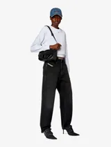 Bandolera mediana de cuero liso color blanco, con solapa frontal que presenta una placa de metal esmaltado con el logo D ovalado en relieve. Incluye correa ajustable para llevar al hombro o cruzada, y compartimento interior amplio con dos secciones planas adicionales.