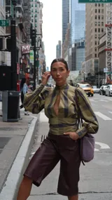 Blusa marrón con cuello alto, detalle de abertura en el escote, mangas largas abullonadas y puños ajustados.