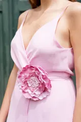 Vestido largo color lila con escote en V cruzado y detalle de flor grande en la cintura.