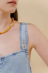 Vestido largo de jean celeste con breteles anchos, corte recto, abertura lateral y bolsillo plaqué en el pecho.