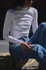 Camiseta blanca de manga larga con cuello alto y corte ajustado.