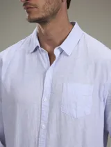 Camisa verde militar de manga larga, confeccionada en mezcla de lino y algodón. Tiene cuello clásico, cierre con botones y un bolsillo en el pecho.