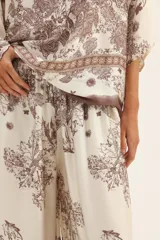 Pantalón palazzo de seda color crema con estampado floral en tonos marrones y cintura elastizada con cordón ajustable.