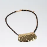 Collar con tira de cuero sintético con estampado animal print y dije rectangular dorado con textura irregular.