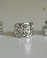 Anillo de plata 950 con diseño calado que simula una textura orgánica o de arrecife, con múltiples aberturas circulares irregulares.