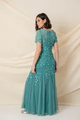 Vestido largo de tul verde con bordado floral al tono, corte sirena y mangas cortas.