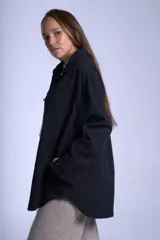 Sobrecamisa negra de gabardina con cuello clásico, cierre frontal abotonado, mangas largas con puños abotonados, dos bolsillos de parche en el pecho y corte recto.