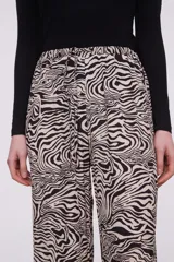 Pantalón de viscosa con estampado abstracto en tonos beige y negro, de corte palazzo y cintura con lazo ajustable.
