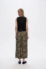 Pantalón capri negro con estampado floral en color crema, de corte ancho y tiro alto.