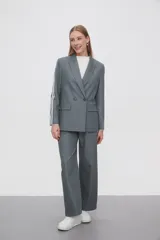 Blazer gris con doble botonadura y solapas de muesca, con dos rayas blancas verticales en las mangas y a lo largo de los pantalones.