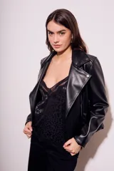 Campera negra estilo biker confeccionada en cuero vegano, con cuello solapa, cierre asimétrico y bolsillos con cremallera.