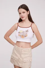 Musculosa cropped blanca con tirantes marrones, estampado de playa con palmeras, sol y flores.
