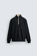 Sudadera negra de tejido con estructura vertical, corte relaxed fit, cuello subido con cremallera frontal color crema, manga larga y acabados en rib.