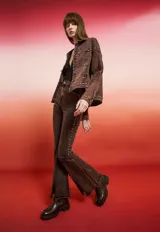 Campera de jean negra de corte holgado con detalles de tachas plateadas en costuras, hombros y puños, y bordado floral blanco en las mangas.