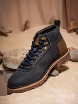 Botines de cuero color azul marino con detalles en marrón y suela marrón. Presenta el logo del Halcón Milenario en el lateral y el logo de Star Wars en el talón.