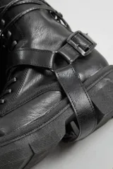 Borcegos negros de ecocuero con cordones y hebilla lateral.