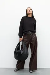 Pantalón ancho de tiro alto confeccionado en símil cuero color negro, con bolsillos frontales.