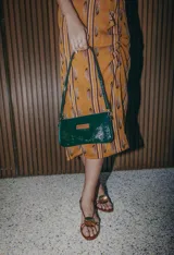 Cartera de mano tipo clutch, color marrón, confeccionada en cuero.