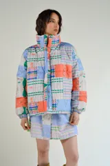 Campera puffer con estampado patchwork multicolor, cuello alto y bolsillos laterales.