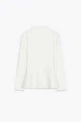 Chaqueta blanca de tejido de punto con cuello solapa y manga larga. Tiene corte evasé en el bajo y cierre frontal con botones dorados.
