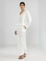 Pantalón de pierna ancha confeccionado en lino color blanco, con cintura elástica con cordón ajustable y bolsillos laterales.