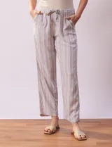 Pantalón largo de lino y rayón a rayas verticales grises y blancas. Tiene pretina elastizada con lazo de ajuste, bolsillos delanteros y traseros.