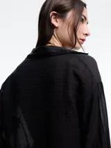 Camisa negra de lyocell y poliamida, con cuello clásico, mangas largas acampanadas con volados y cierre frontal con botones.