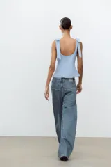 Top blanco de tejido elástico con escote cuadrado y tirantes con lazos decorativos. Tiene forro interior y cierre lateral con cremallera oculta.