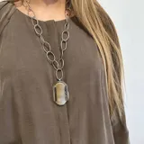 Collar con cadena de alpaca, presenta un dije ovalado de nácar engarzado.