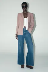 Blazer color rosa palo, sin solapa, de corte recto y manga larga. Presenta bolsillos de ojal en el delantero y cierre frontal con gancho metálico.