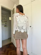 Blusa color crudo calada de crochet, de mangas largas y cuello redondo.
