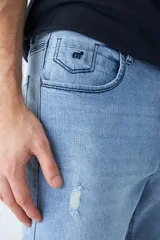 Jean celeste de calce recto, con roturas en las rodillas, tiro medio, cinco bolsillos y logo bordado en el bolsillo pequeño delantero.