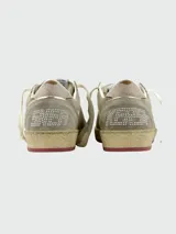 Championes Golden Goose BallStar de gamuza color gris con estrella dorada en el lateral, cordones blancos y suela con detalles en rojo.