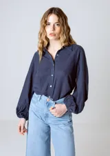Camisa azul marino de manga larga con puños elásticos, cuello clásico y cierre frontal con botones.