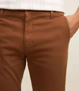 Pantalón de vestir color marrón, de corte recto, con bolsillos laterales y traseros. Se ajusta a la cintura con cinturón de cuero marrón.